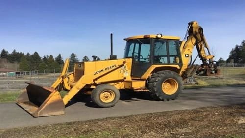 John Deere backhoe loader excavator with front loader bucket and rear digging arm outdoors
